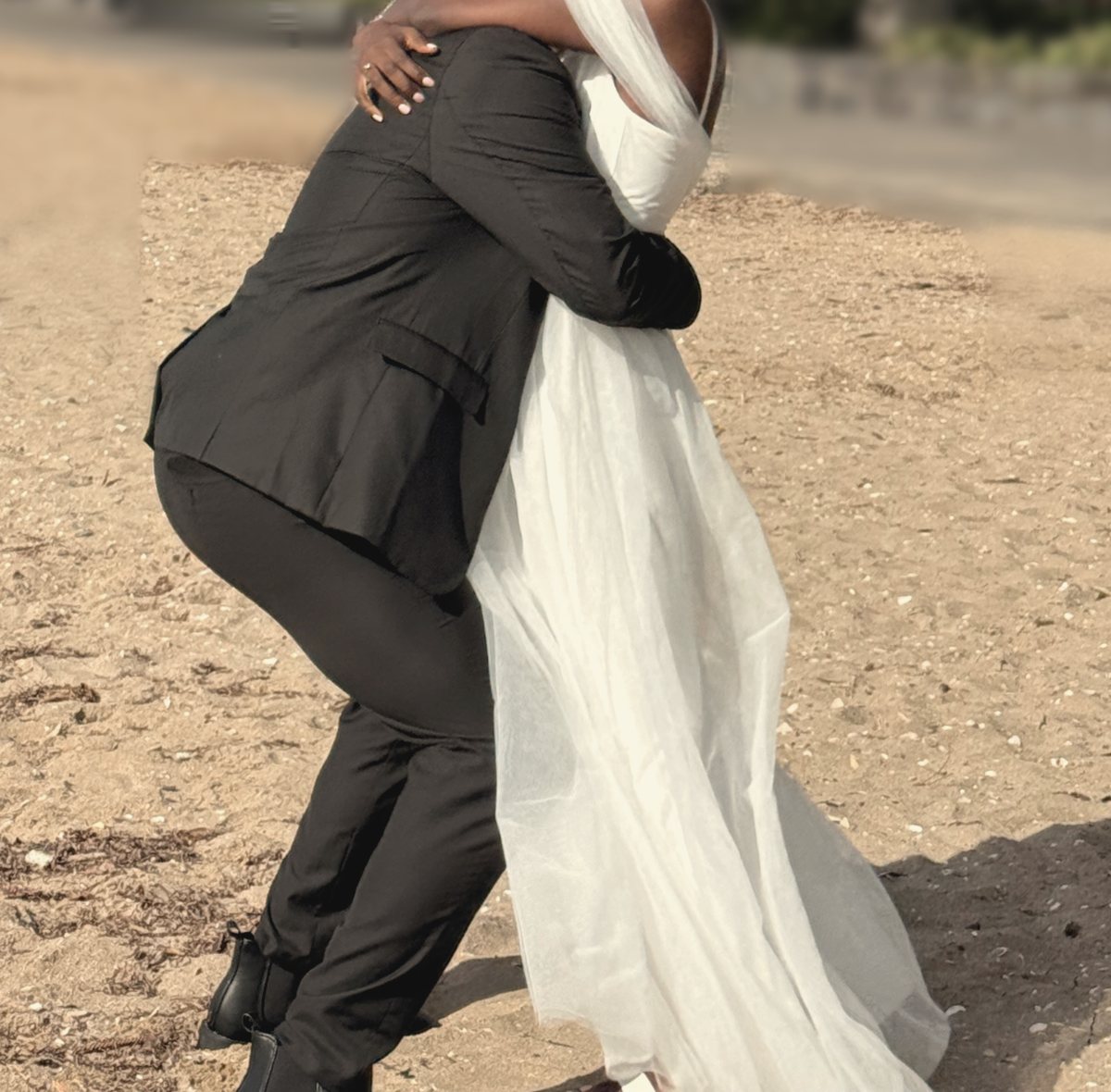 A couple embracing on the beach, her dress swinging out
